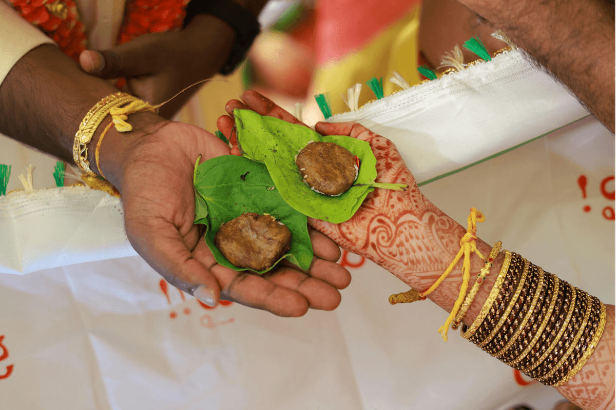 A bride and groom holding bellam and jeelakarra on betel leaves — a Telugu wedding ritual